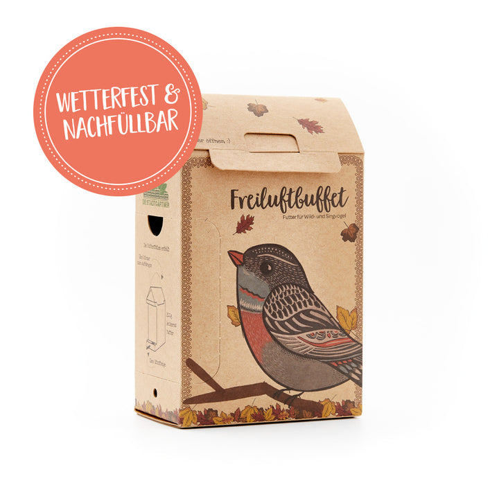 Verpackung für Vogelfutter mit der Aufschrift "Freiluftbuffet", wetterfest und nachfüllbar, verziert mit dem Bild eines Vogels und Herbstblättern.