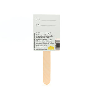 Rückseite eines Samentütchens mit Holzstab, auf dem Angaben über Wildblumen-Saatgut und Platz für „von:“ und „für:“ stehen.