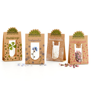 Vier braune Geschenktüten mit kleinen Gläschen und getrockneten Blumen, jeweils mit den Aufschriften "Glücksbringer", "Trostspender", "Wunscherfüller" und "Lieblingsmensch" von Die Stadtgärtner.