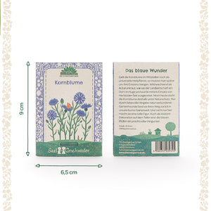 Zwei Saatgutverpackungen für Kornblumen mit floraler Illustration und Produktbeschreibung auf Deutsch, daneben Maßangaben 9 cm hoch und 6,5 cm breit.