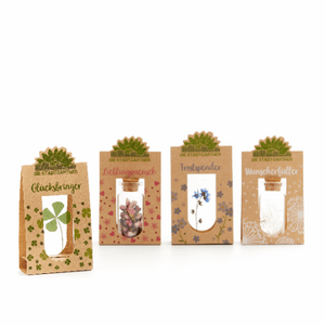 Vier kleine Geschenktüten mit Aufschriften "Glücksbringer", "Lieblingsmensch", "Trostspender", und "Wunscherfüller" jeweils mit verschiedenen Pflanzenmotiven.