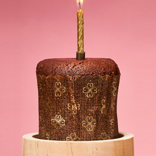 Geburtstagskuchen in Form eines Baumstammes mit einer brennenden Kerze darauf.