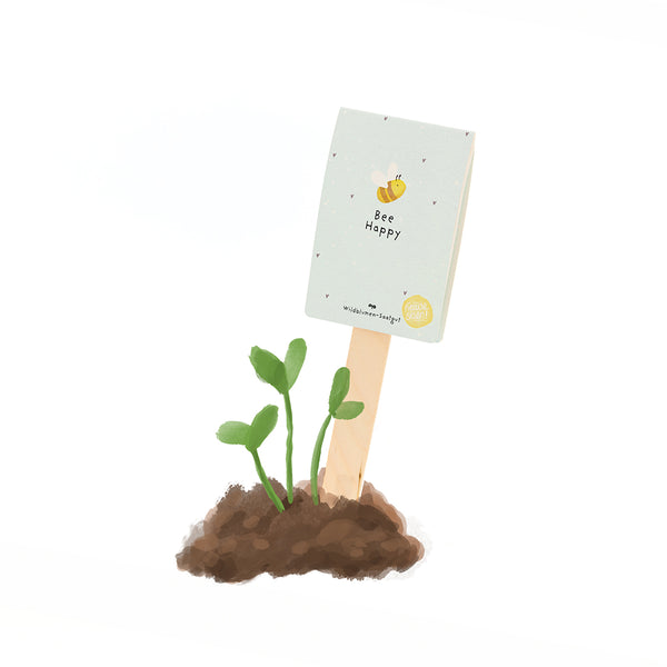 Ein kleines Pflänzchen wächst aus Erde, daneben steckt ein Holzschild mit der Aufschrift "Bee Happy" und einer gezeichneten Biene.