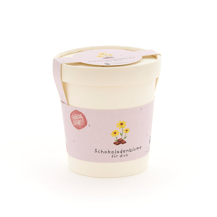 Pflanzbecher mit rosa Etikett, auf dem "Schokoladenblume für dich" und eine Zeichnung einer Blume über einem Schokoladenstück zu sehen ist.
