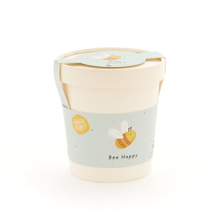 Beiger Becher mit hellblauem Etikett, auf dem eine gezeichnete Biene und der Schriftzug "Bee Happy" zu sehen sind.
