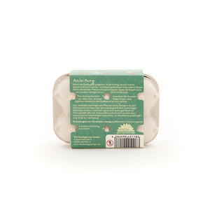 Eine kleine Verpackung mit Anleitungstext und Barcode, vermutlich für Saatgut, auf weißem Hintergrund.