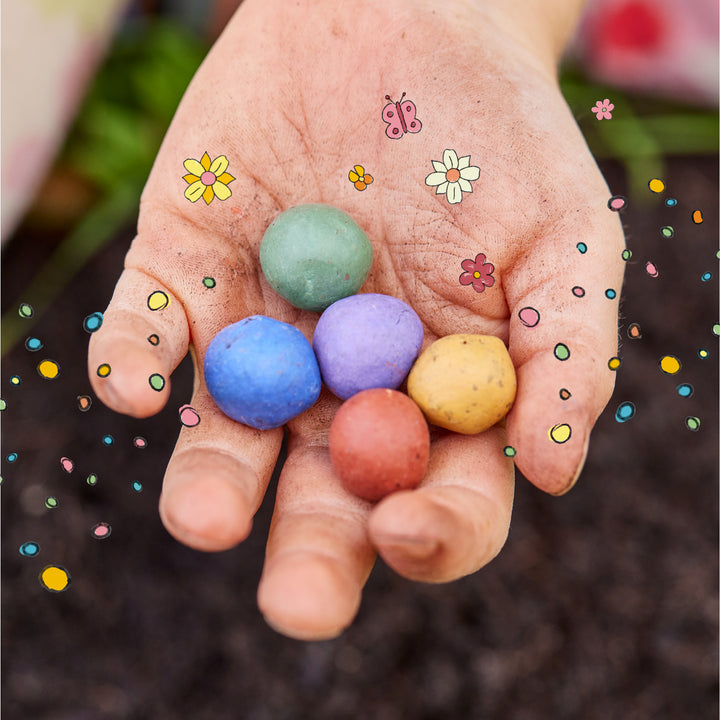 Eine Hand, die bunte Kreideier hält, mit gezeichneten Blumen und Schmetterlingen umgeben.