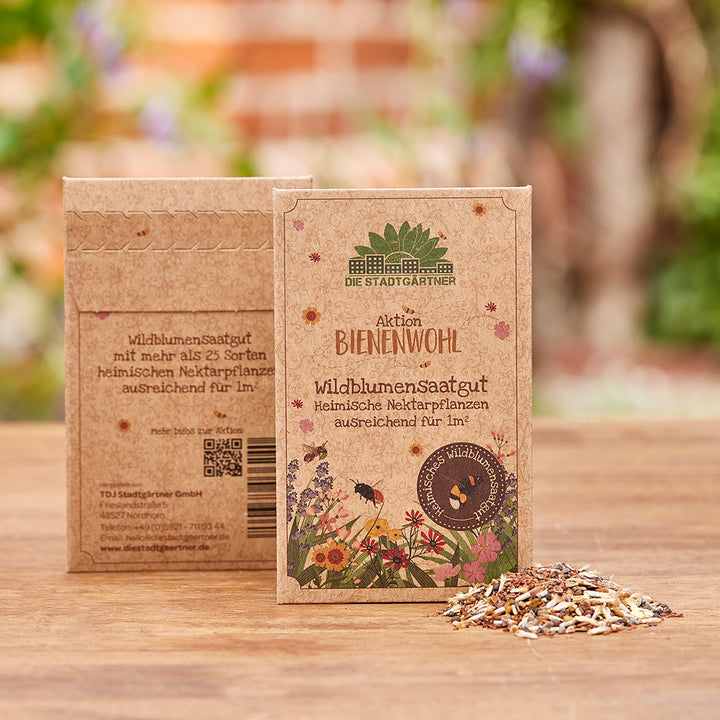 Wildblumensaatgut-Verpackungen auf Holzoberfläche mit ausgestreuten Samen im Vordergrund.