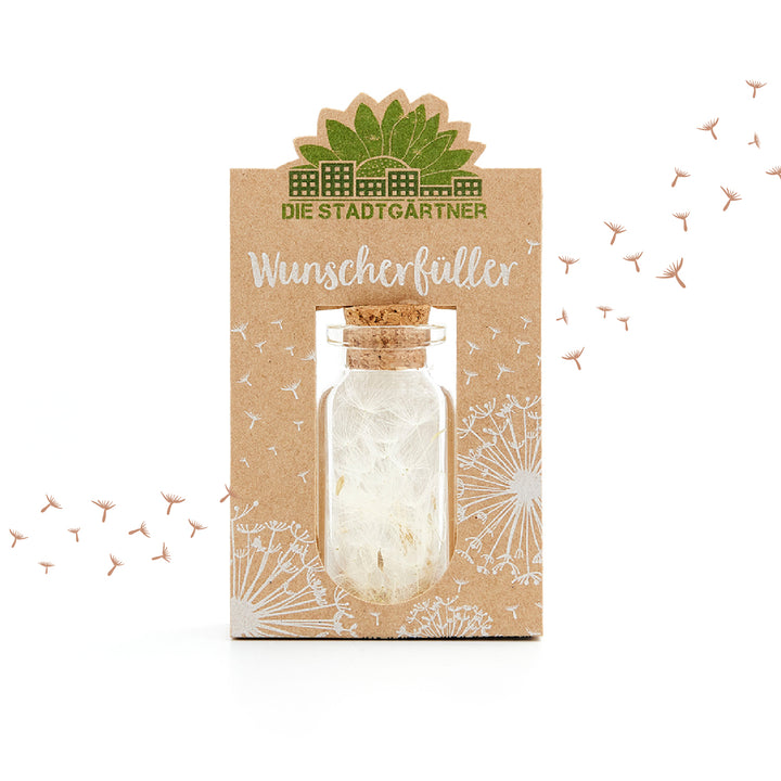 Produktverpackung 'Wunscherfüller' mit einer kleinen Flasche und Pusteblumensamen, umgeben von einem weißen Löwenzahndesign auf braunem Hintergrund.