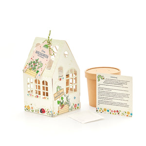 Set mit einem kleinen dekorativen Gewächshaus, einem Blumentopf, einer Anleitung und einem Samentütchen für den Anbau von Tomaten.