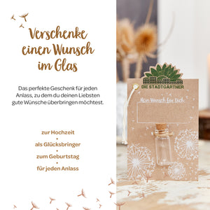 Werbebild für ein Geschenkkonzept "Wunsch im Glas" mit Texten, einem Gläschen an einer Karte und Trockenblumen im Hintergrund.