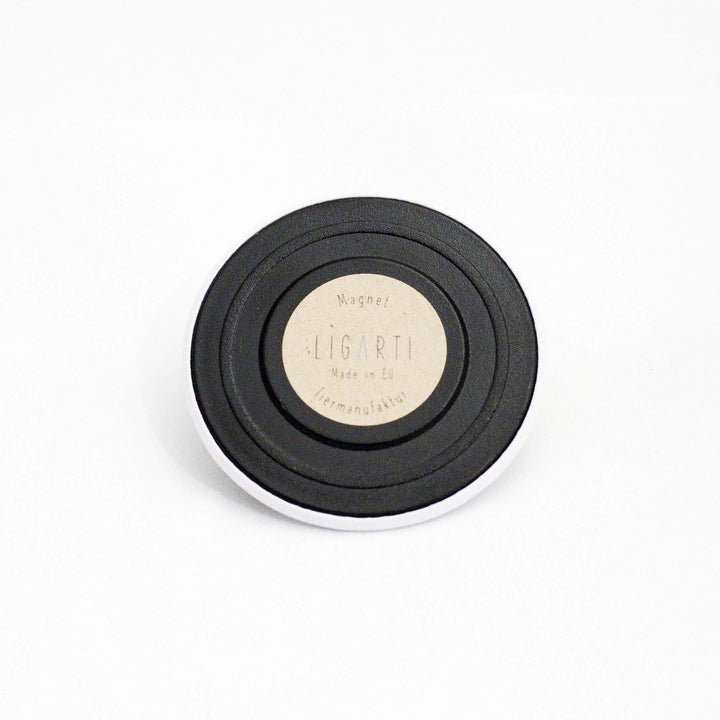 Schwarzer runder Magnet mit dem Aufdruck "LIGARTI Made in EU" auf einem hellen Hintergrund.