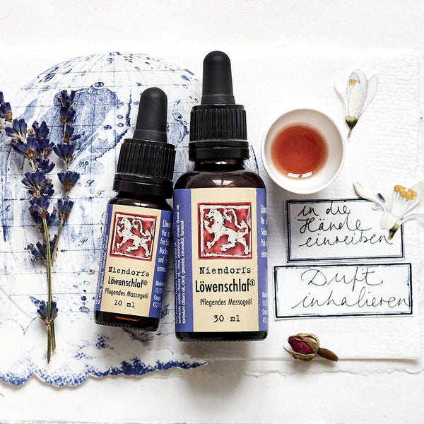"Ätherische Öle auf weißem Hintergrund mit Lavendelzweigen, einer Teetasse und handgeschriebenen Notizen"
