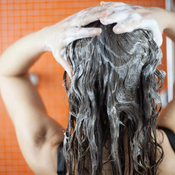 Person wäscht sich die Haare mit Shampoo.