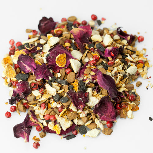 Bunter loser Tee mit getrockneten Blüten, Fruchtstücken und Gewürzen auf weißem Hintergrund.