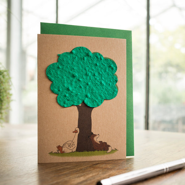 Handgefertigte Grußkarte mit einem grünen Baum aus Papier und darunter Hühnern und einem Hund.
