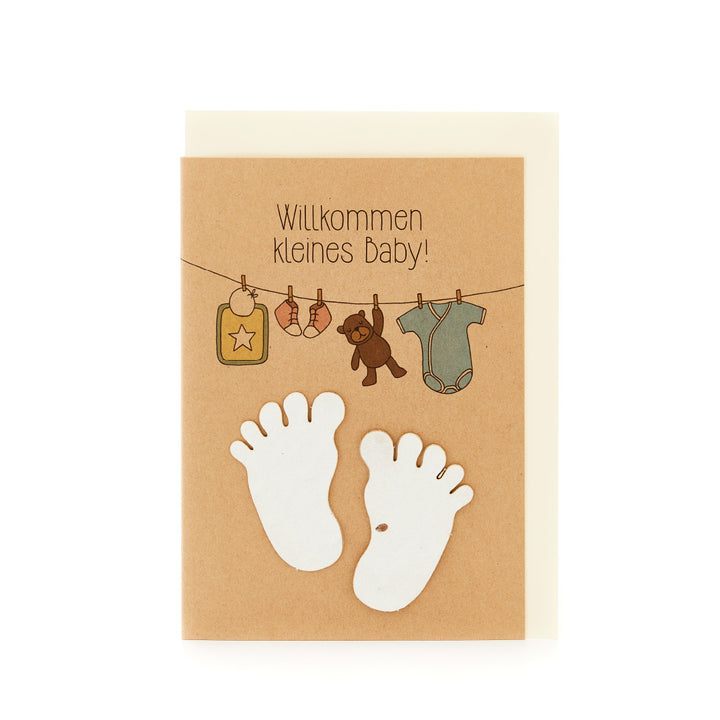 Glückwunschkarte zur Geburt mit der Aufschrift "Willkommen kleines Baby", Babyfüßen und aufgehängten Babykleidungsstücken.