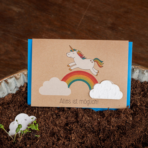 Grußkarte mit Einhorn und Regenbogen auf Erdboden, Text "Alles ist möglich!"