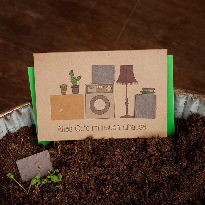 Glückwunschkarte mit Topfpflanzen, Waschmaschine und Lampe, Text: Alles Gute im neuen Zuhause!