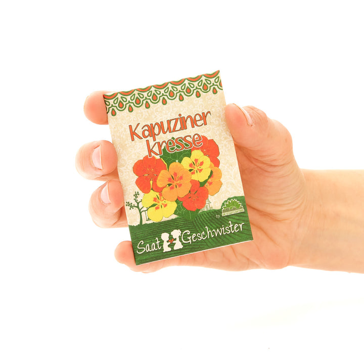 Hand hält eine Packung Kapuzinerkresse-Saatgut