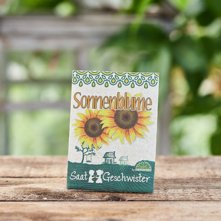 Saattütchen mit der Aufschrift "Sonnenblume" und dem Logo "Saar & Geschwister" auf Holzoberfläche mit unscharfem grünen Hintergrund.