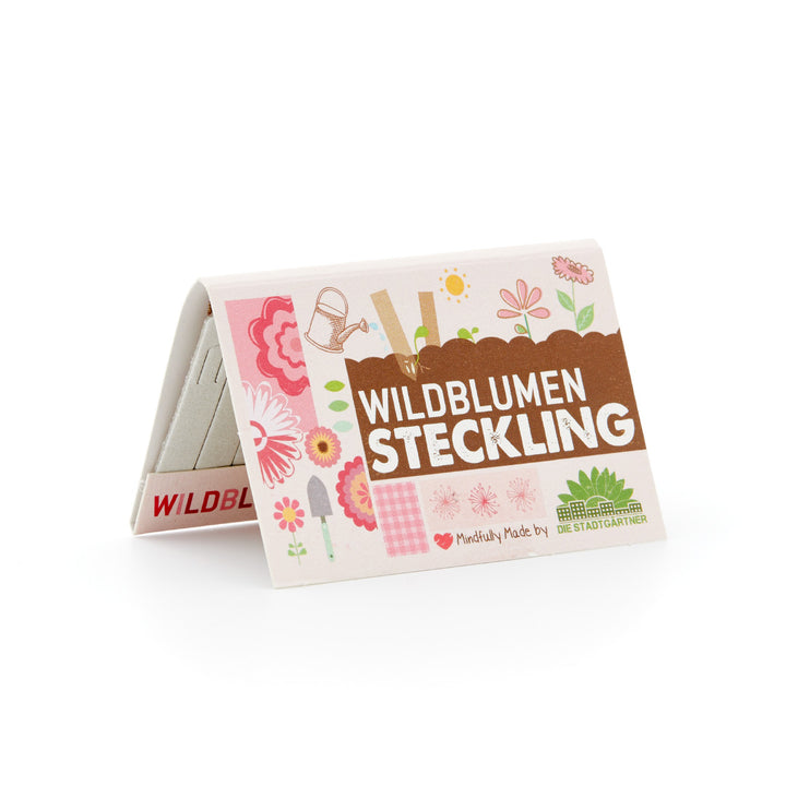 Verpackung für "Wildblumen Steckling" mit Blumen- und Gartengeräte-Illustrationen.