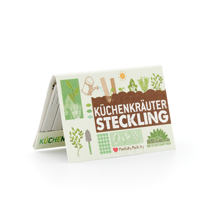 Verpackung mit der Aufschrift "Küchenkräuter Steckling" und Gartenwerkzeug-Grafiken auf weißem Hintergrund.