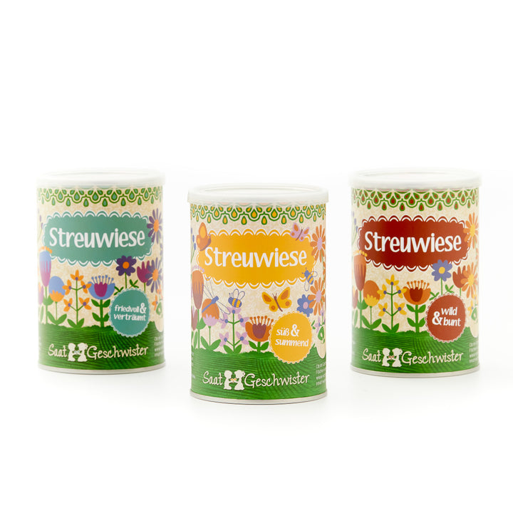 Drei verschiedene Dosen der Marke 'Streuwiese' mit Blumenmotiven und Beschriftung in Grün, Orange und Rot.