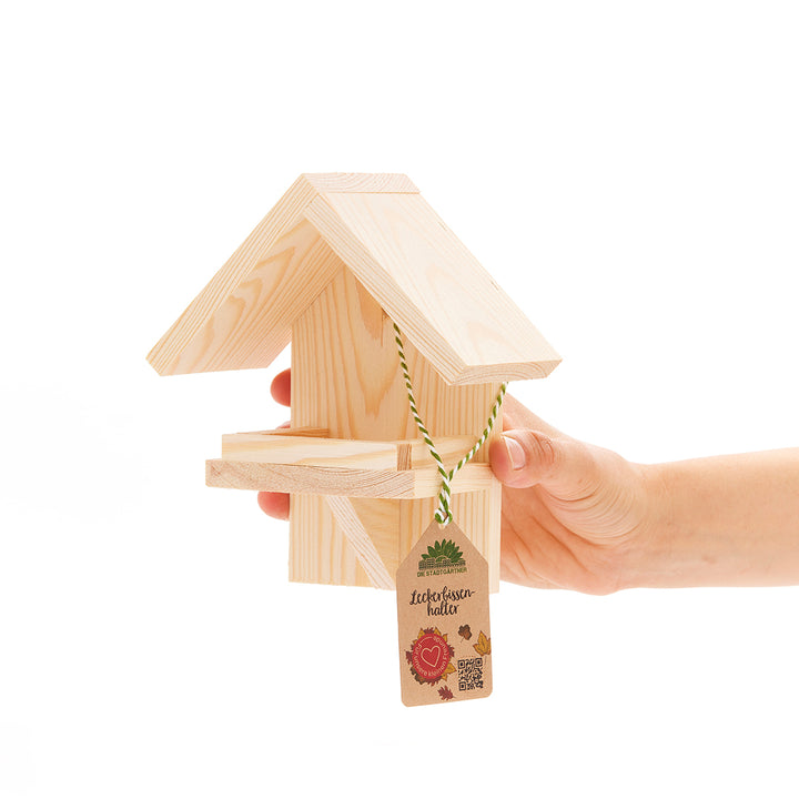 Holzvogelhaus gehalten von einer Hand mit Preisschild.